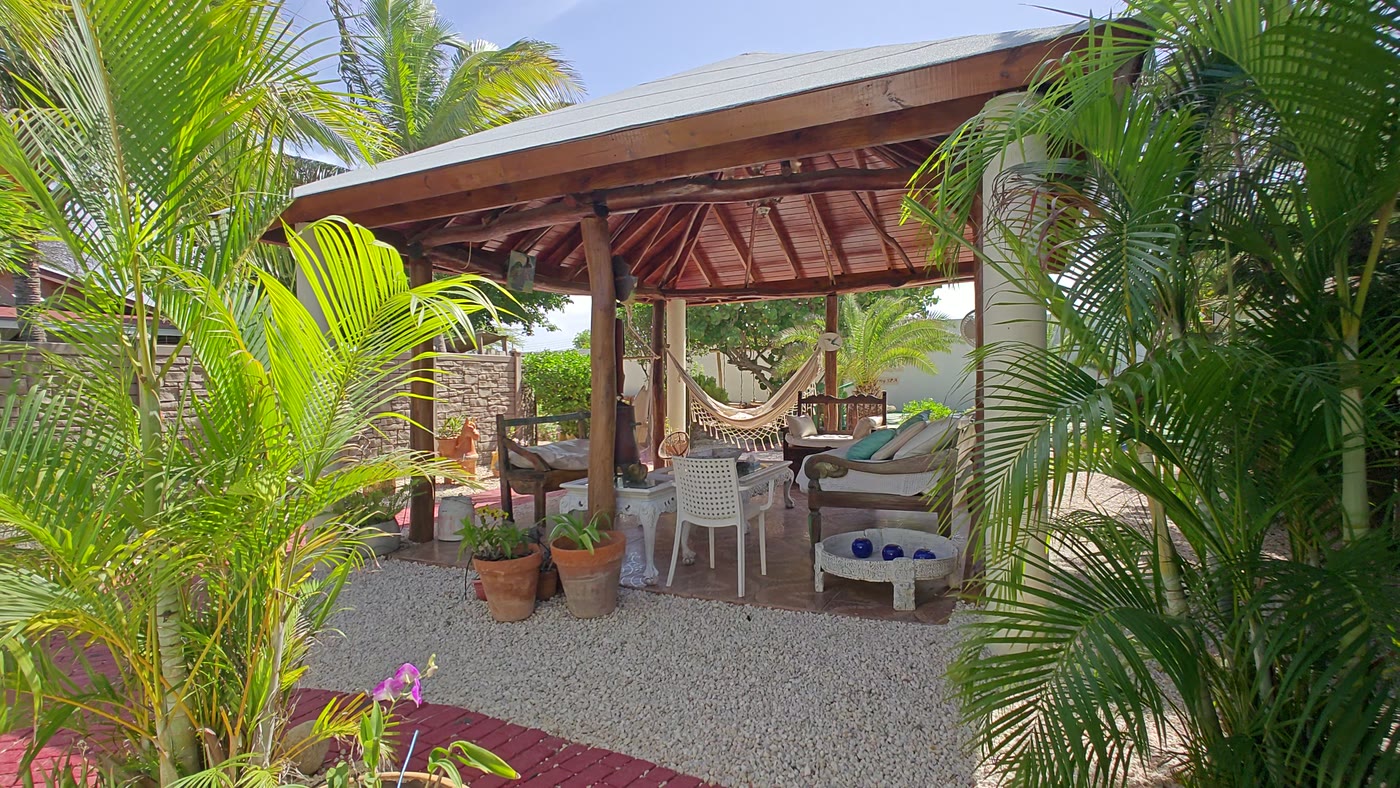 The thatched gazebo in the back garden, with a hammock and loungers in the shade